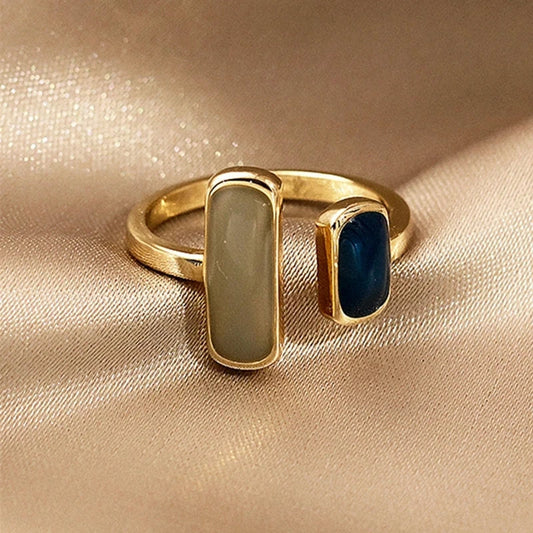 Goudkleurige ring met twee rechthoekige stenen in contrasterende tinten. Deze elegante ring van Brenzo straalt tijdloze klasse uit en is het perfecte accessoire om elke outfit te verrijken. Ideaal voor dagelijks gebruik of speciale gelegenheden.
